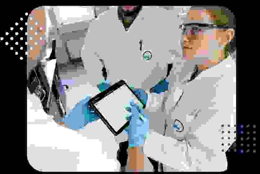 Drei Personen in Laborkitteln schauen auf ein Tablet und diskutieren.