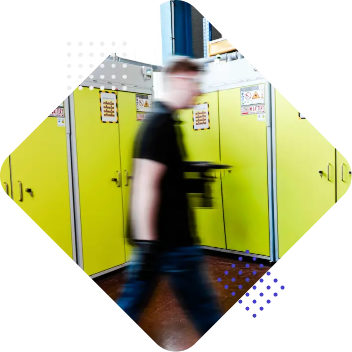 A blurred figure walking past bright yellow cabinets in an industrial setting.
