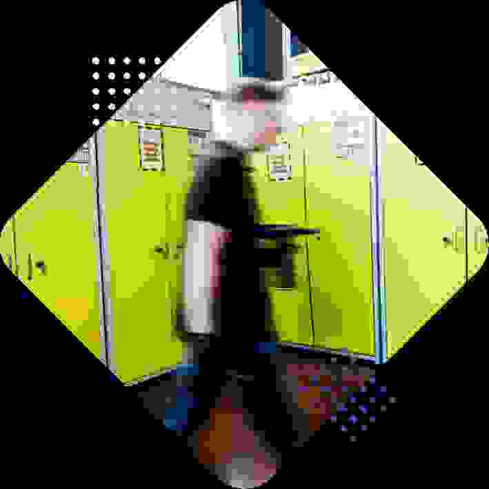 A blurred figure walking past bright yellow cabinets in an industrial setting.