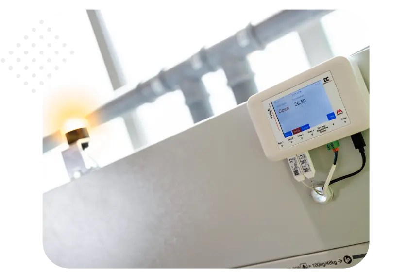 Display screen showing system status and readings, with a warning light on the side and pipes in the background.