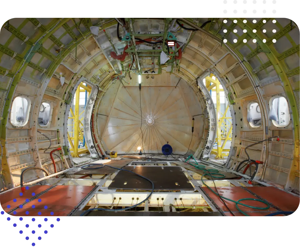 Interior view of an aircraft fuselage, showcasing the structure and components with visible lighting and pipes.