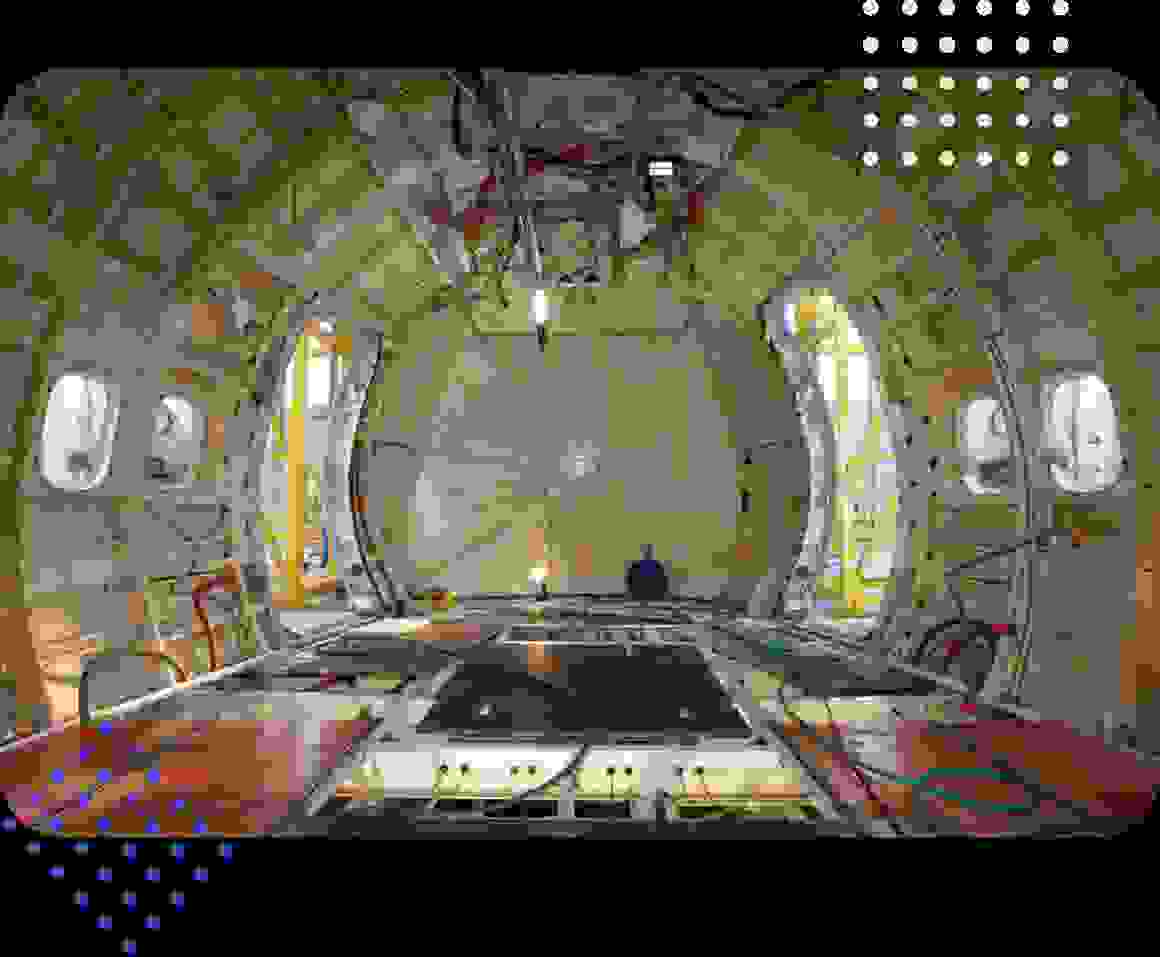 Interior view of an aircraft fuselage, showcasing the structure and components with visible lighting and pipes.