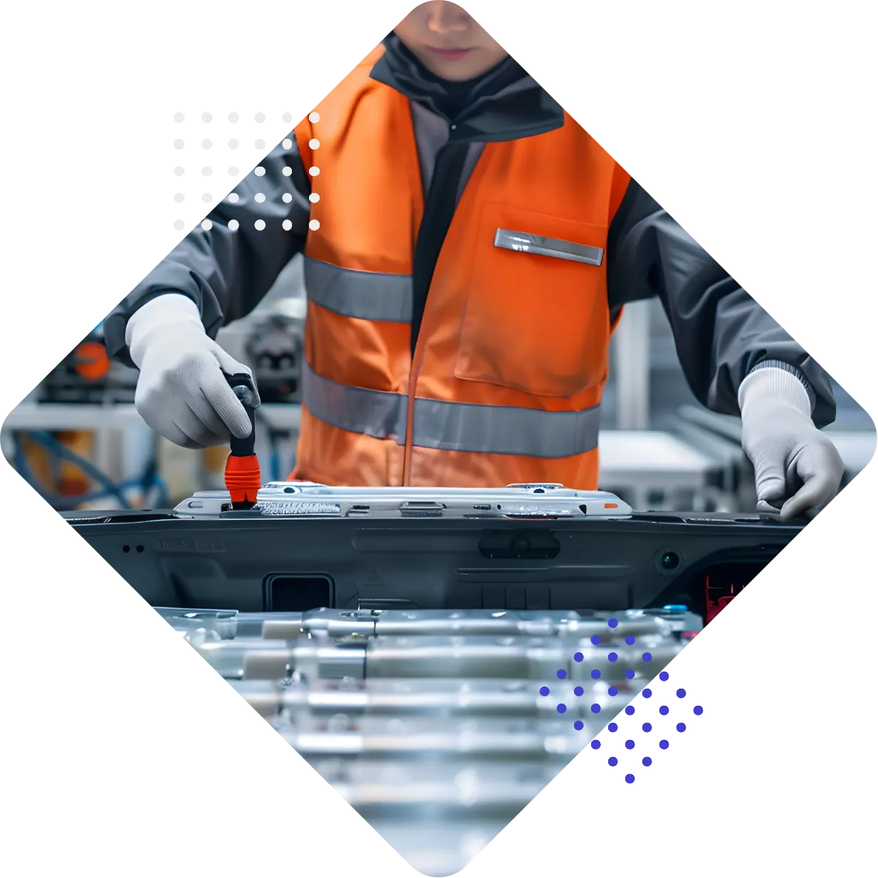 A worker in an orange safety vest applies a marker to a component in a manufacturing environment.