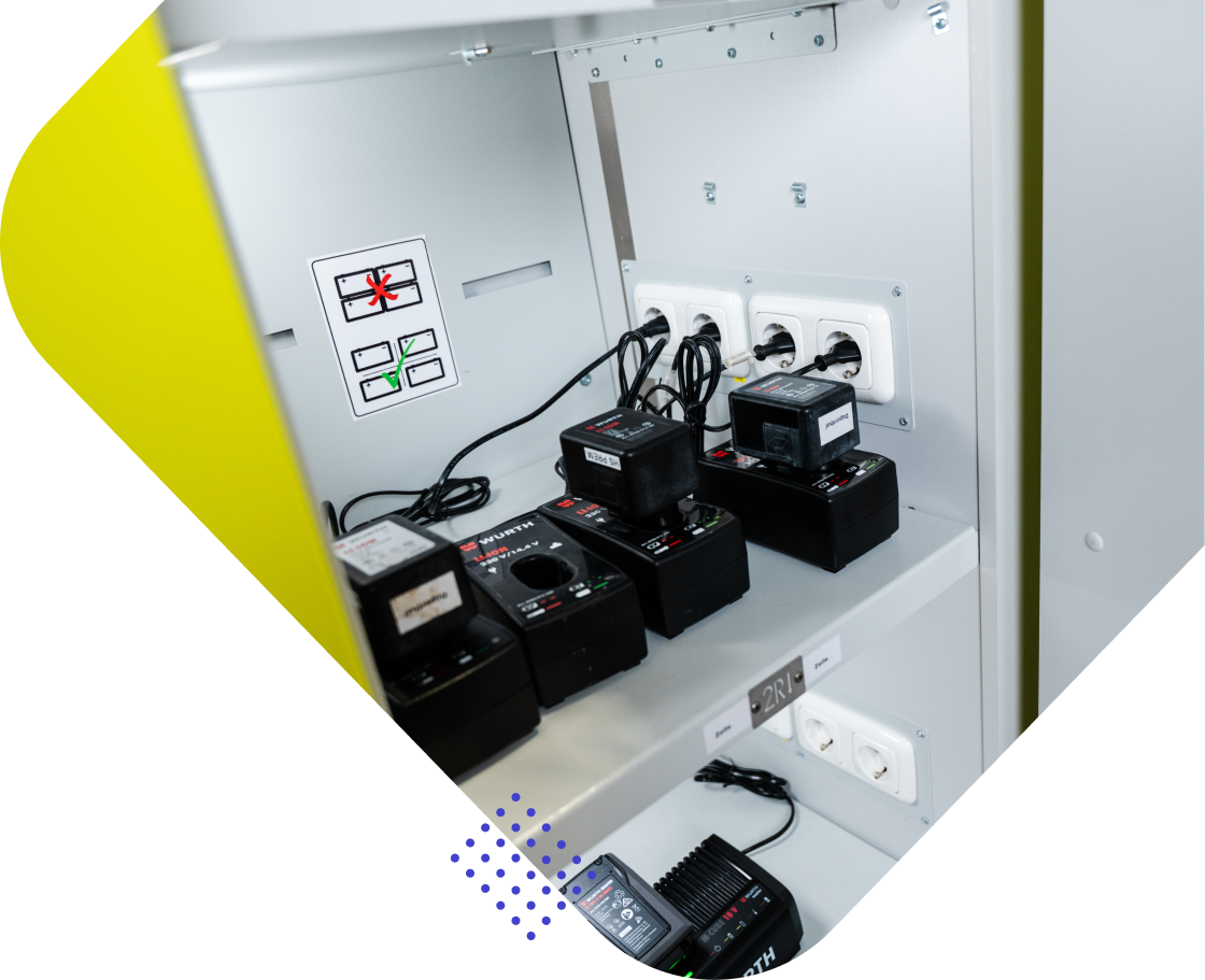 Ein offener Schrank mit Akkuladestationen, mehreren Ladegeräten und Steckdosen.