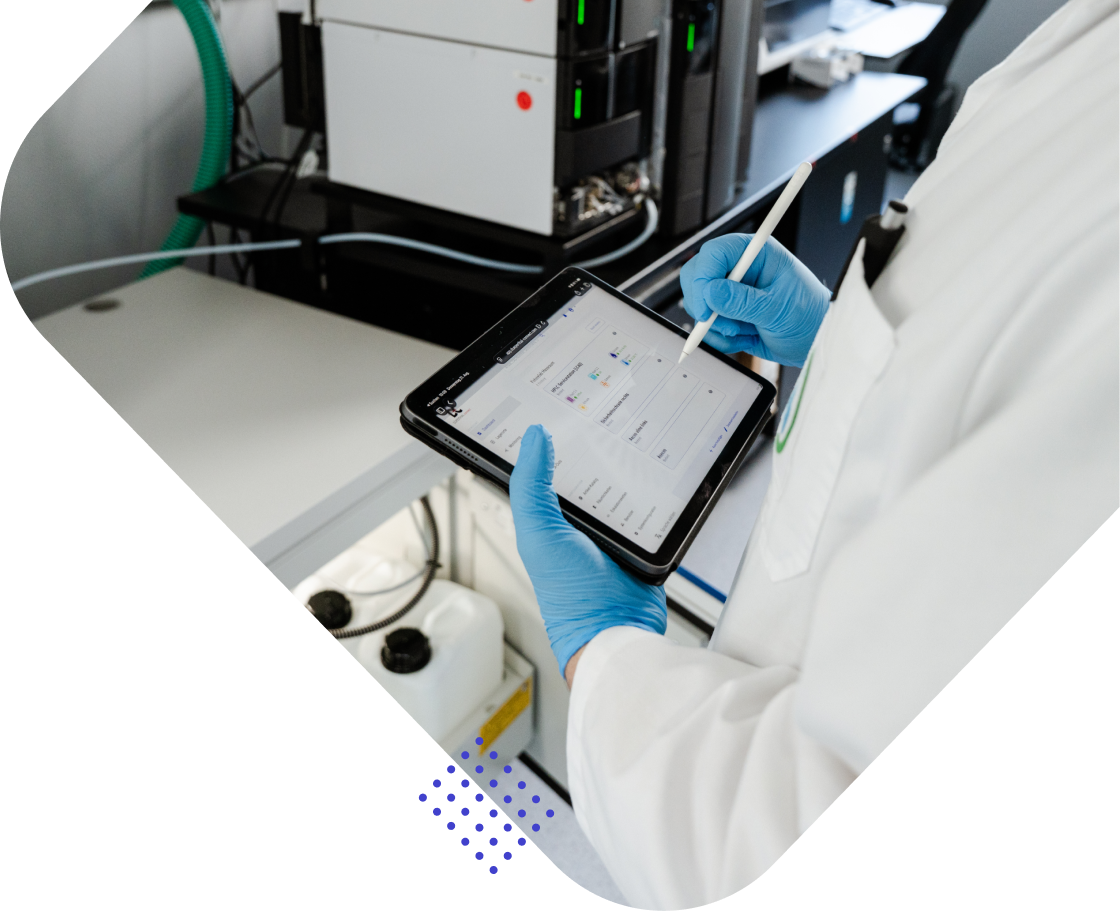 Ein Wissenschaftler in einem weißen Laborkittel hält ein Tablet und nutzt einen Stylus. Im Hintergrund sind Laborausrüstungen sichtbar.